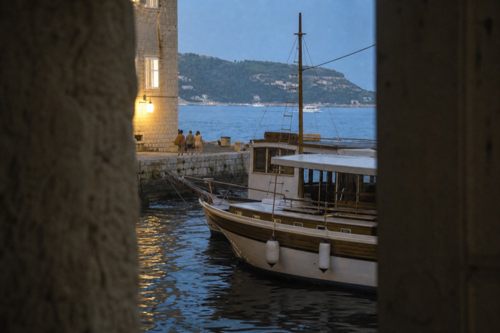 Wooden tourist boat moored at a stone quay with island hills behind