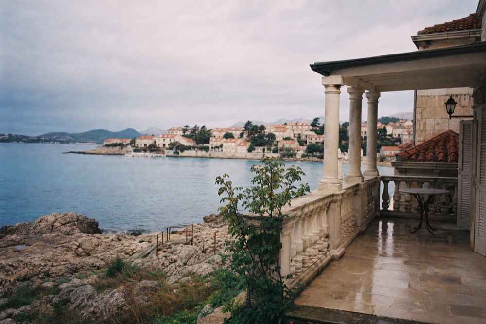 Elegant hotel balcony with a view over red rooftops to the sea