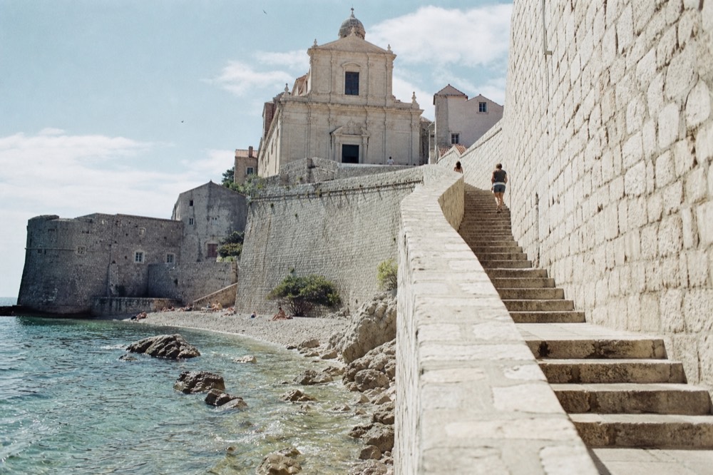 Curved stone staircase rising toward a baroque church facade in Dubrovnik
