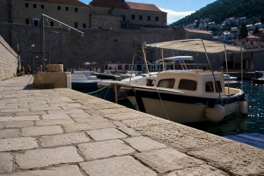 Harbour in Dubrovnik Old Town with boats moored beside stone quays and old buildings
