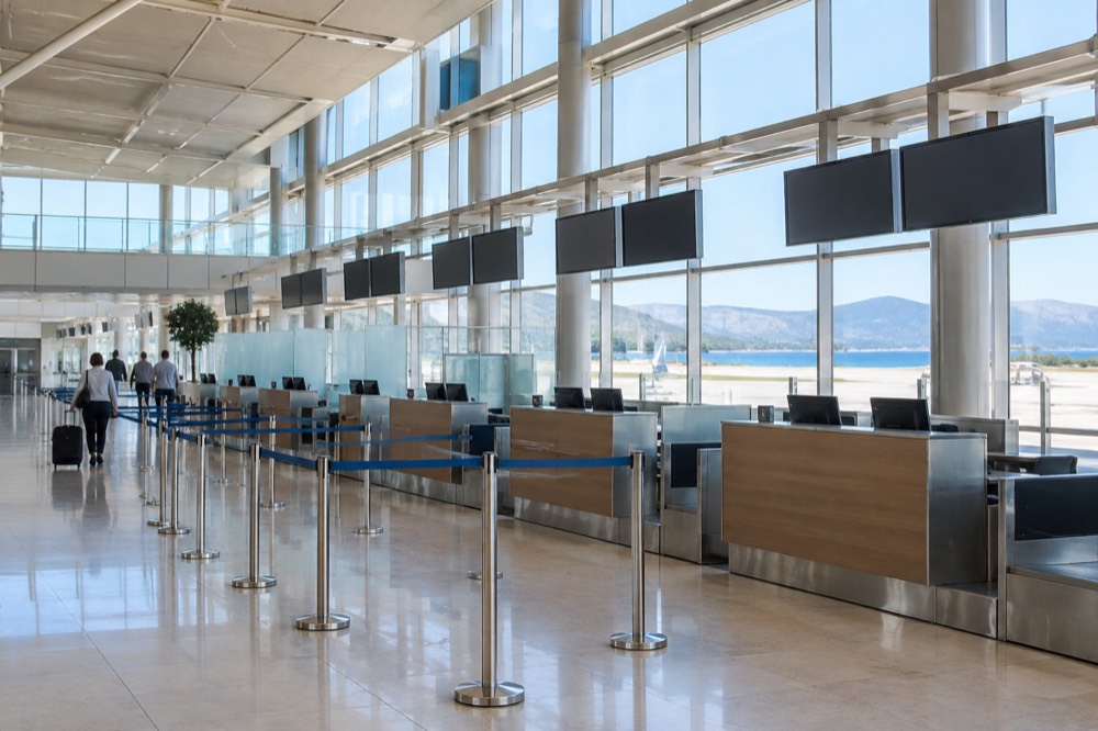A row of check-in desks under a high ceiling in a bright, almost empty airport terminal