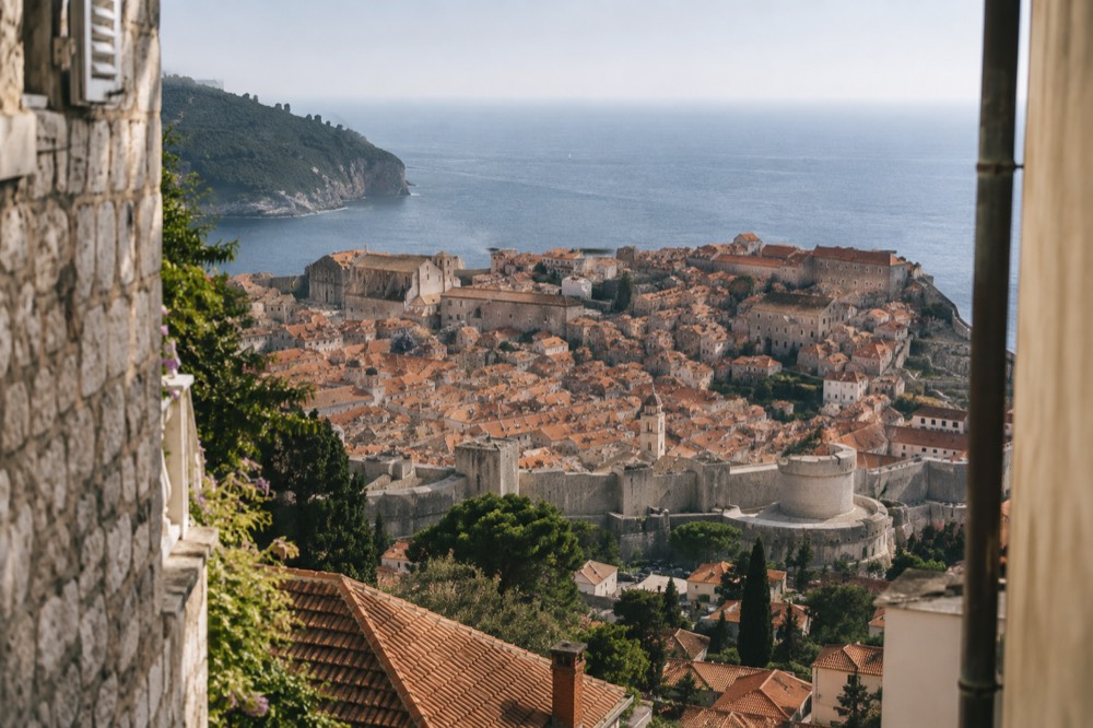 Terracotta rooftops of a walled old town seen from a hillside above the sea