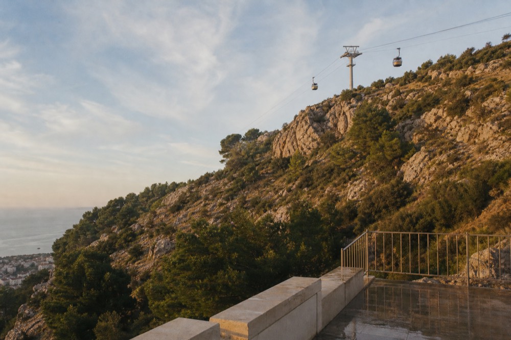 Cable car cabins ascending the hillside above Dubrovnik at golden hour