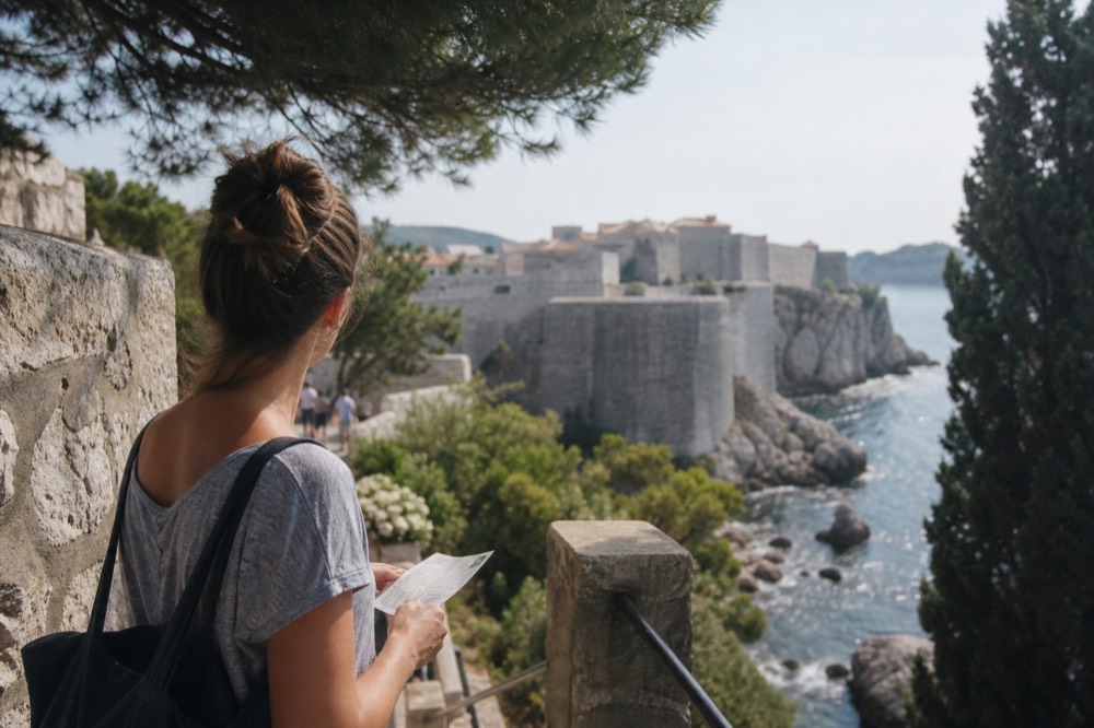 A traveller holding a printed ticket and looking at the city walls from the Pile Gate entrance