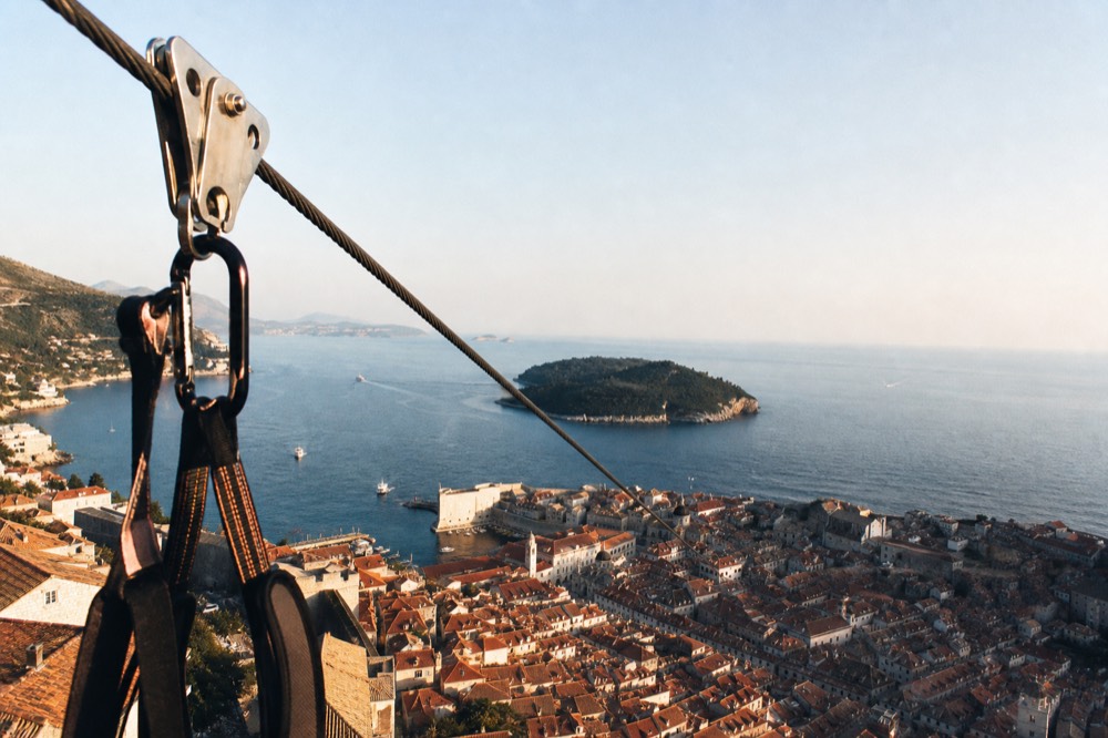 A close-up of the zipline cable and harness with the Old Town rooftops visible below
