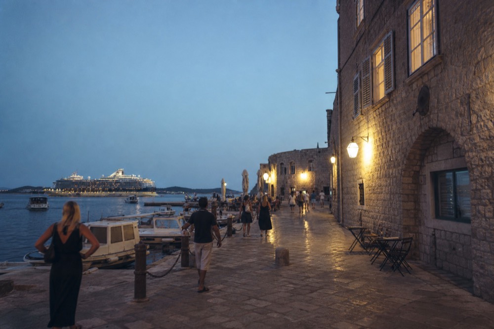 The Old Town harbour with a cruise ship visible in the distance, and visitors walking along the quay