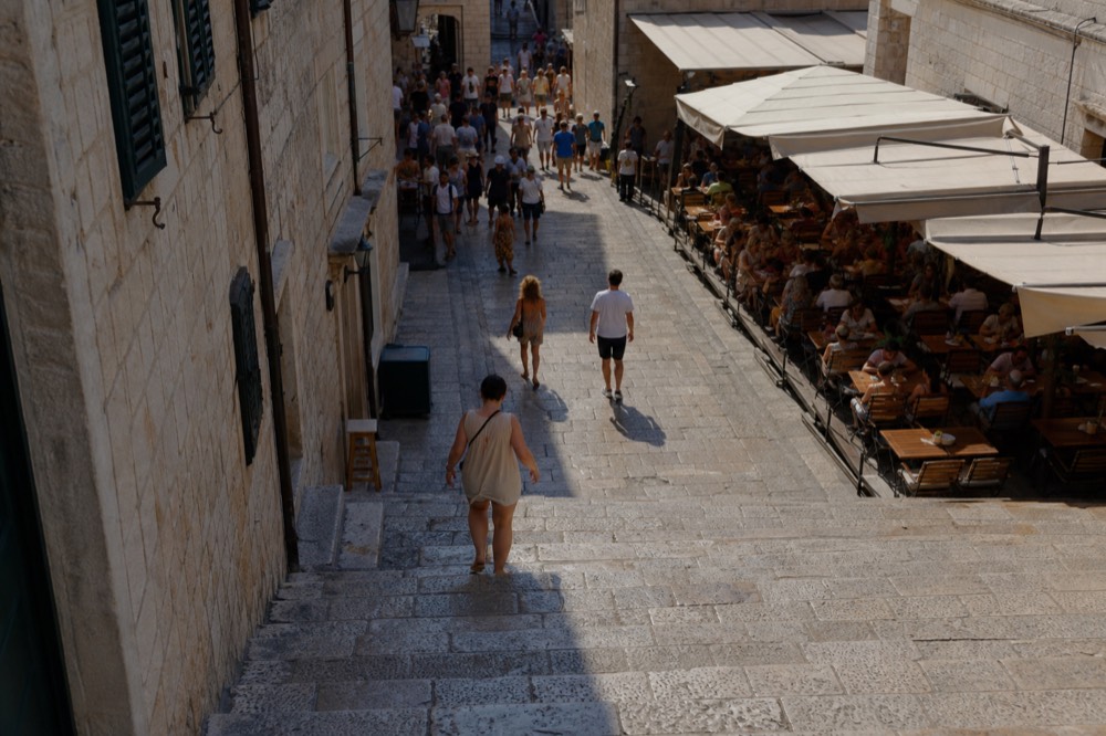 Crowded limestone street in Dubrovnik Old Town with restaurant tables
