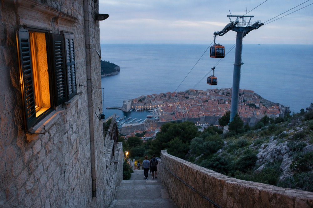 Cable car cabins above Dubrovnik climbing toward Mount Srd at golden hour