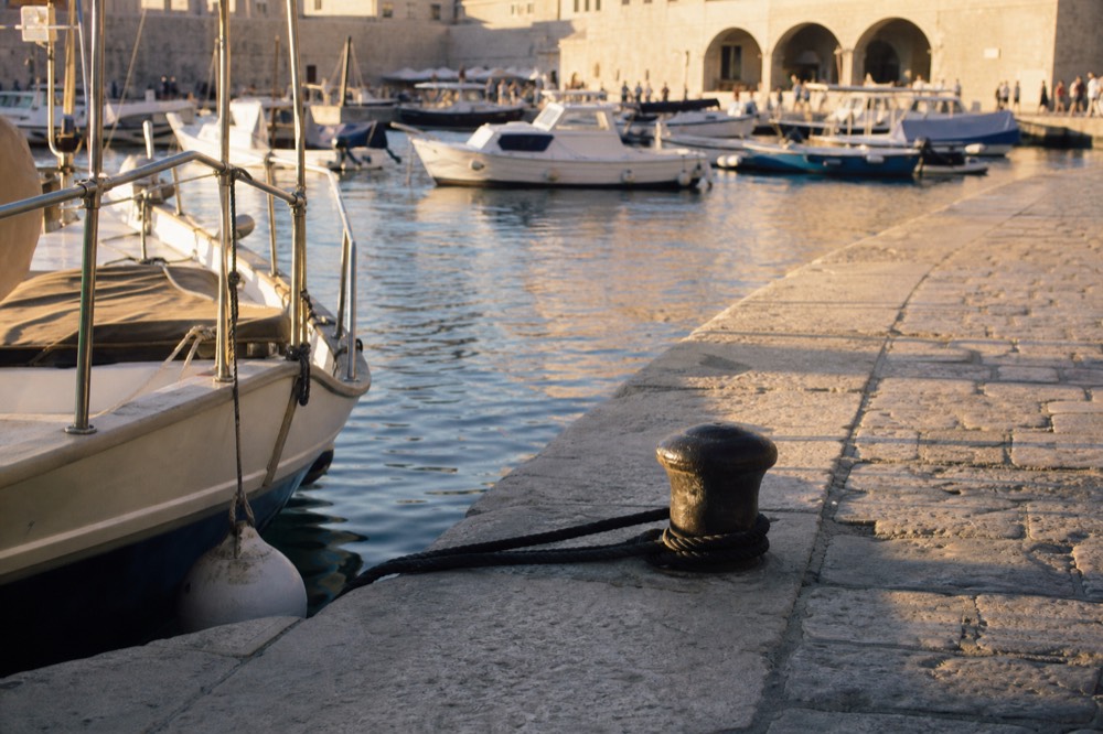 Warm evening light on Dubrovnik harbour with boats moored along the quay