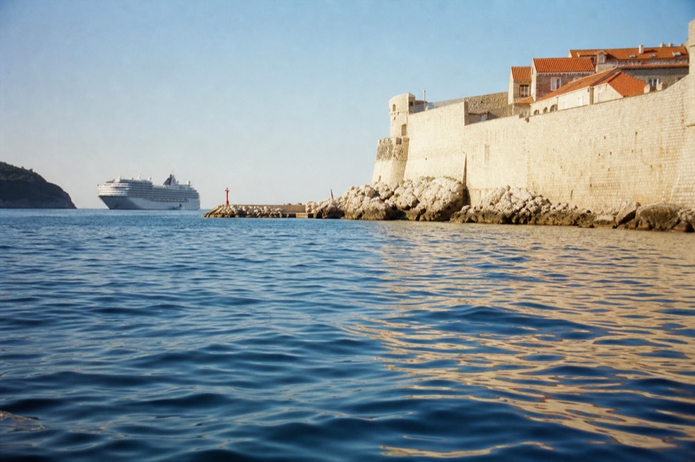 A cruise ship anchored outside Dubrovnik Old Town harbour in late afternoon light