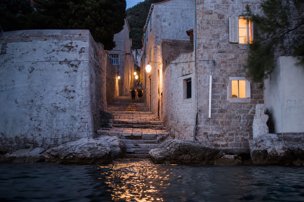 A narrow stone lane with worn steps rising between old buildings