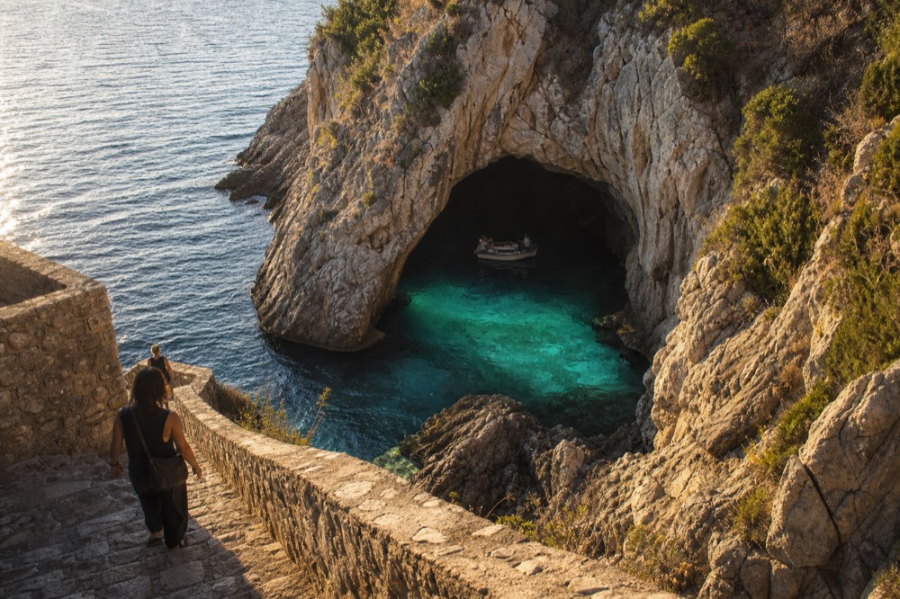 Turquoise water glowing inside a sea cave with a small boat inside