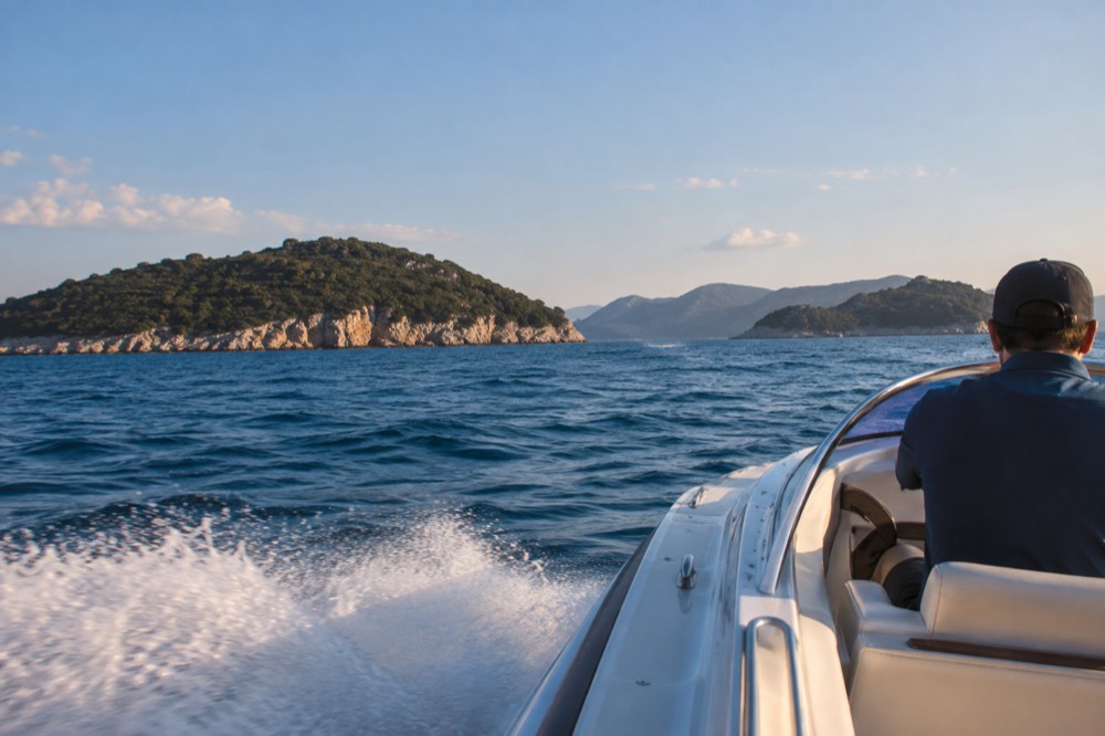 A speedboat on open water between islands on a sunny day