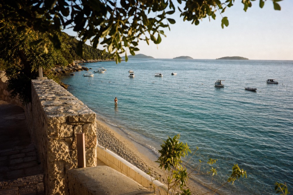 Clear shallow water over sand at a beach with small boats anchored offshore