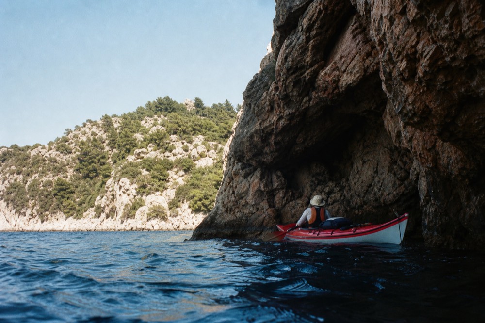 A kayak floating beside a rocky cave entrance near sunset