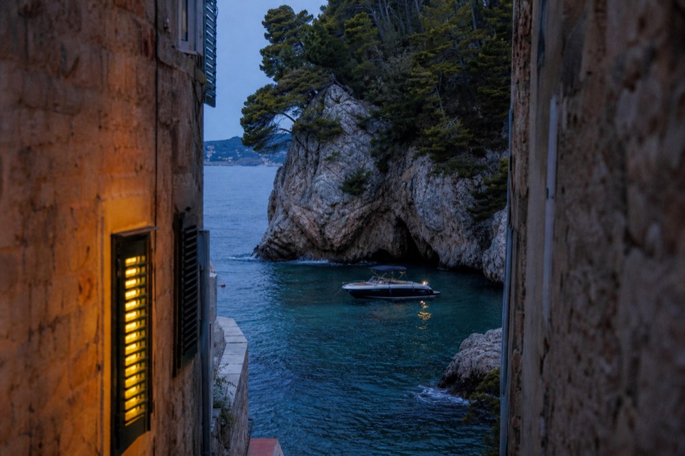 A speedboat anchored beside a rocky cave entrance on the Adriatic coast