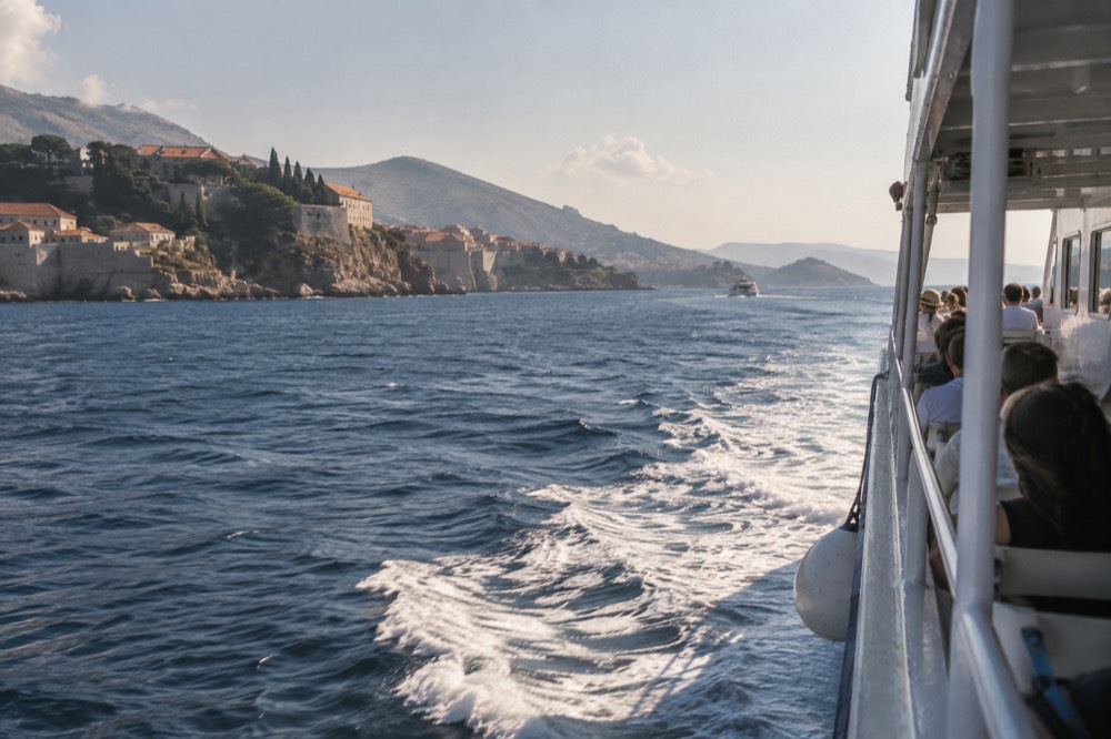 A passenger ferry travelling along a coastline with islands in the distance