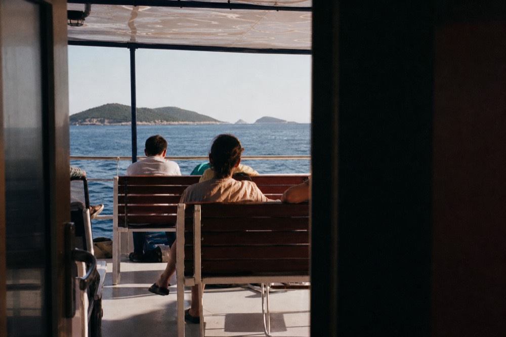 Passengers relaxing under shade on a boat deck with islands on the horizon