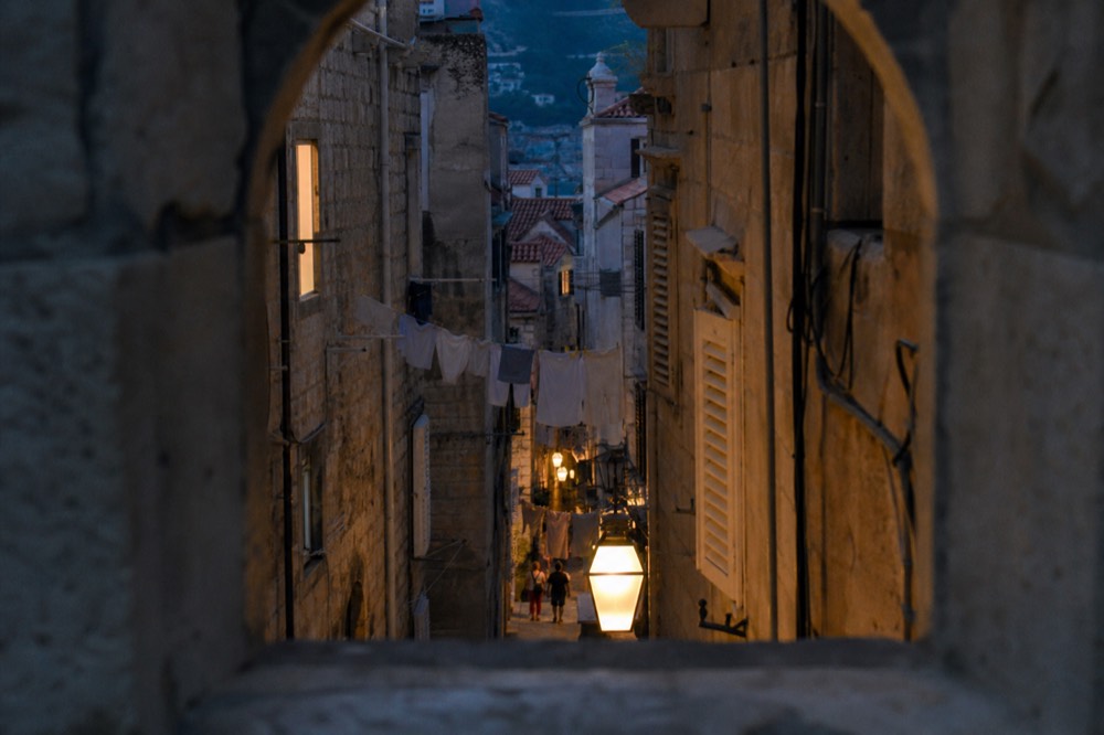 Narrow stone lane in Dubrovnik Old Town with laundry lines and warm evening light