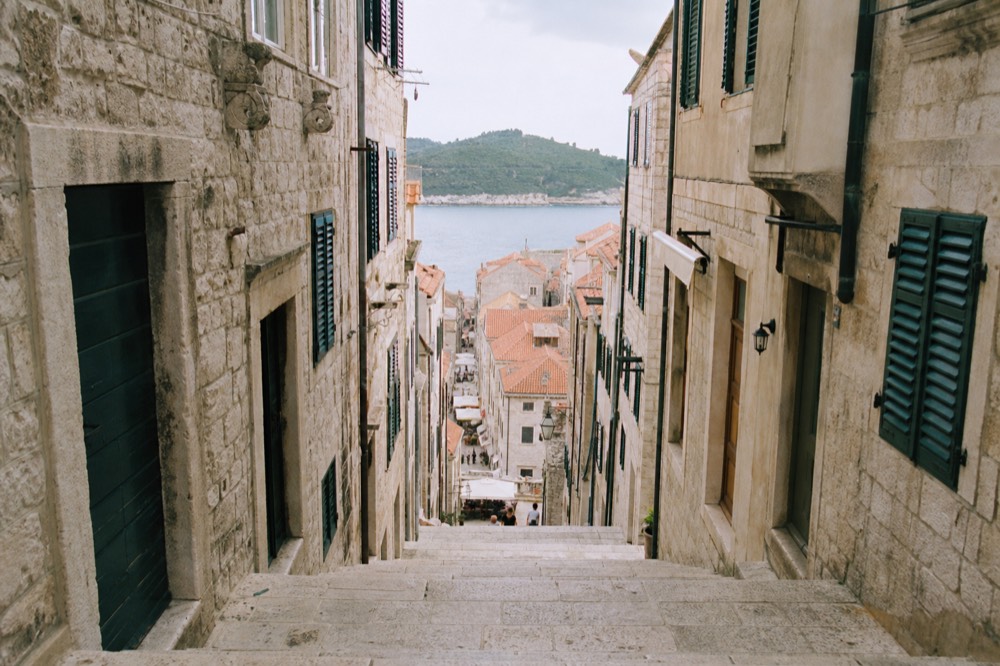 A stone street inside Dubrovnik Old Town with limestone pavement and tall shuttered buildings