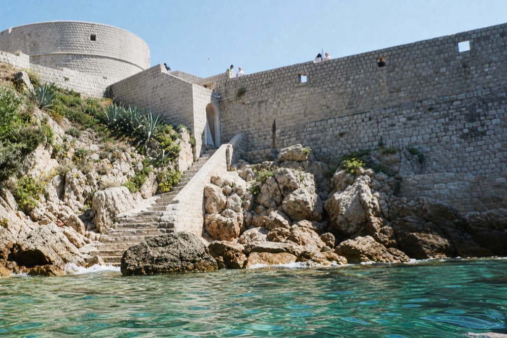 A stone staircase and fortified wall in Dubrovnik Old Town under bright sky