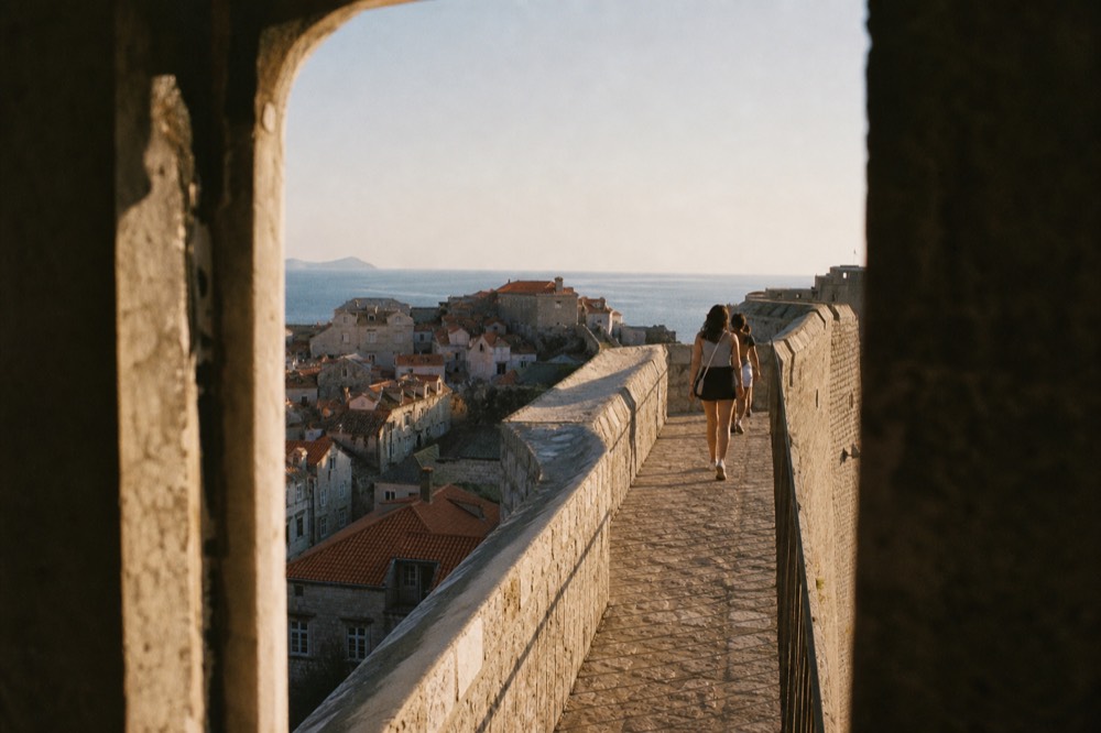 Visitors walking the Dubrovnik city walls above the terracotta rooftops of the Old Town