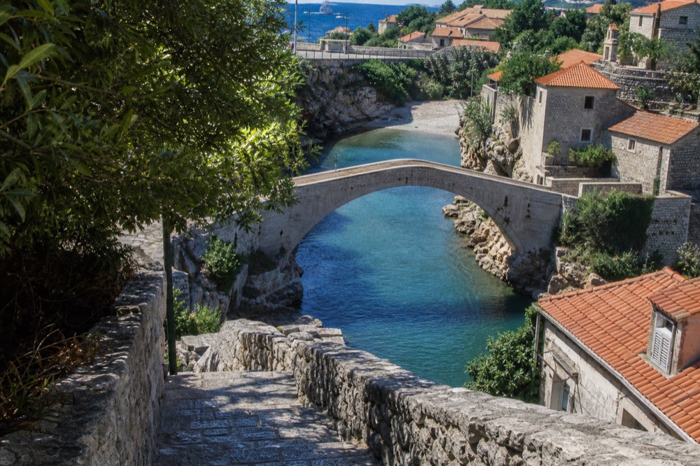 Old stone bridge arching over a turquoise river between rocky hills