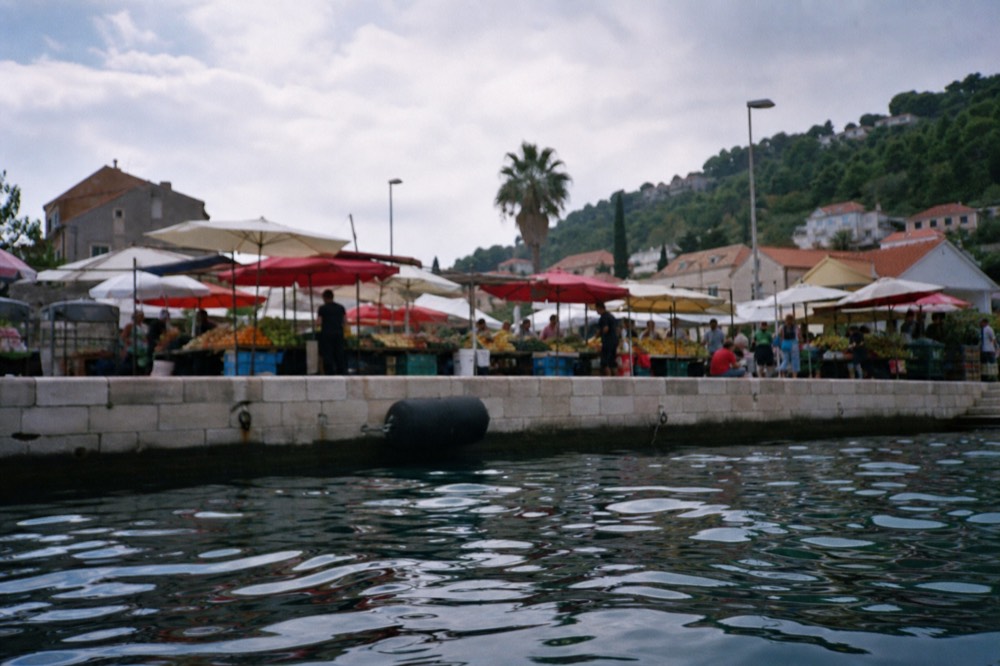 Market stalls with fresh vegetables and fruit under awnings in Gruž