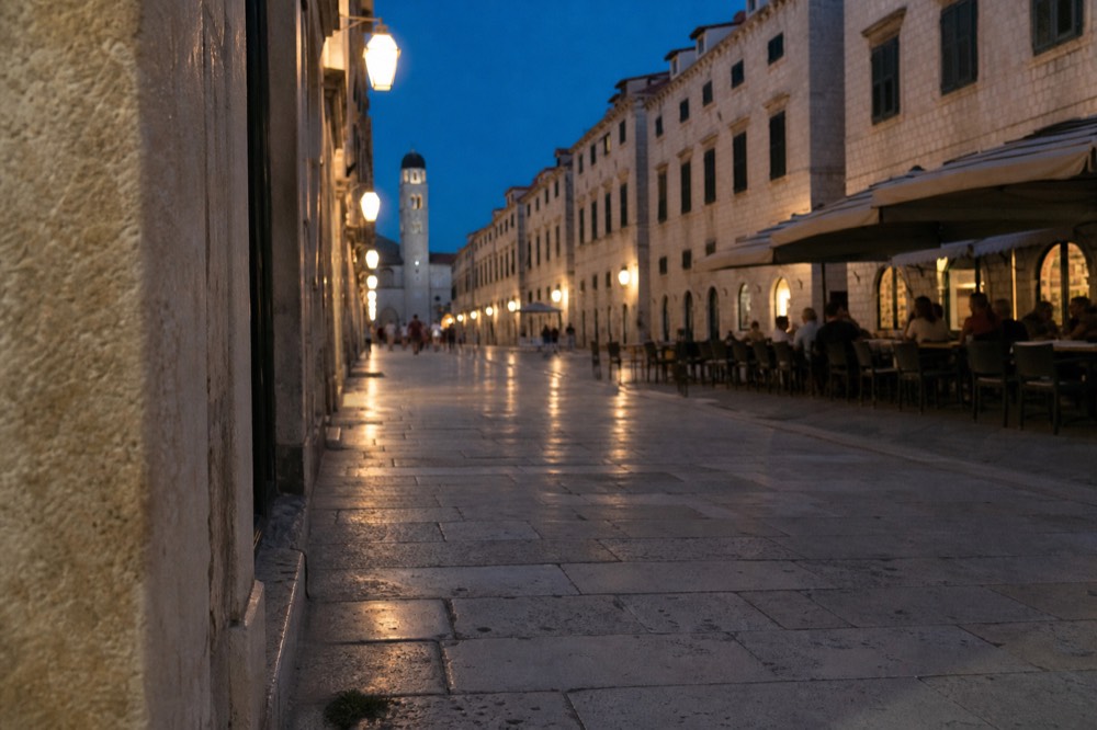 The wide limestone-paved Stradun street lined with café tables and stone facades