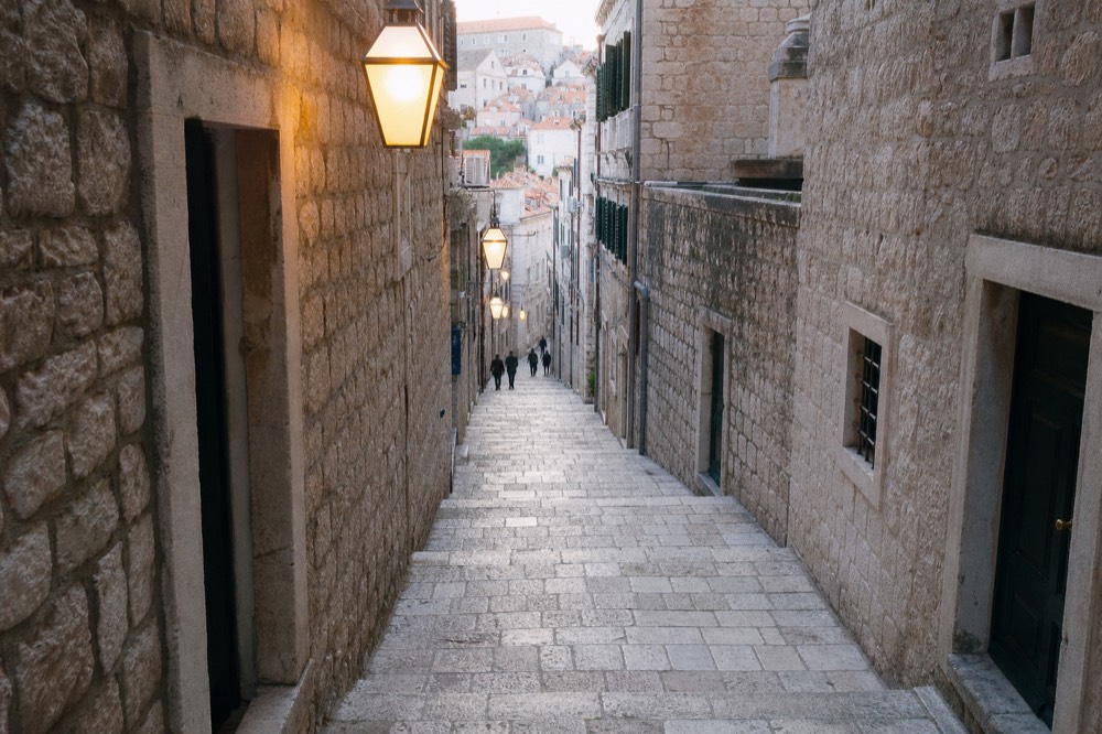 Empty stone side street in Dubrovnik Old Town in winter with warm lamplight