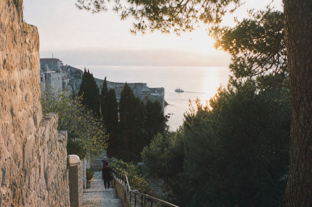 A small boat on calm water outside Dubrovnik harbour at sunset in winter