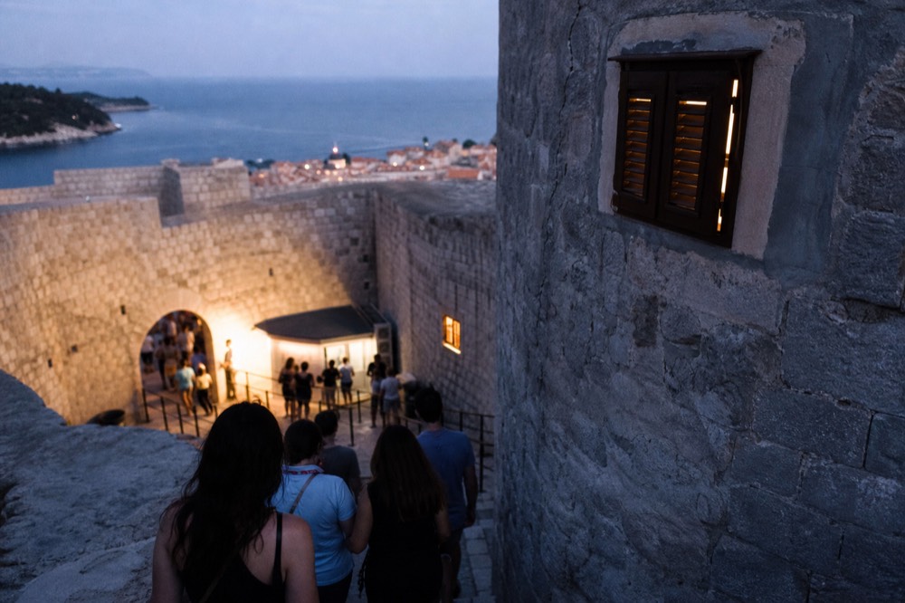 Ticket booth at a stone gate entrance with visitors queuing
