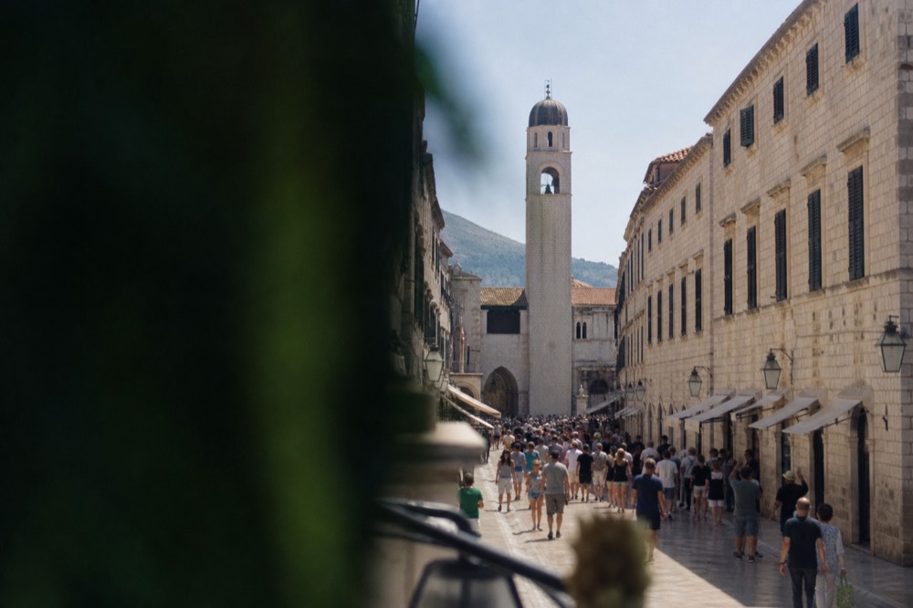 The Stradun crowded with visitors walking between stone buildings at midday