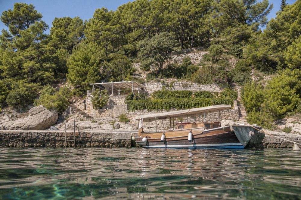 Wooden boat moored at a stone quay with island coastline behind