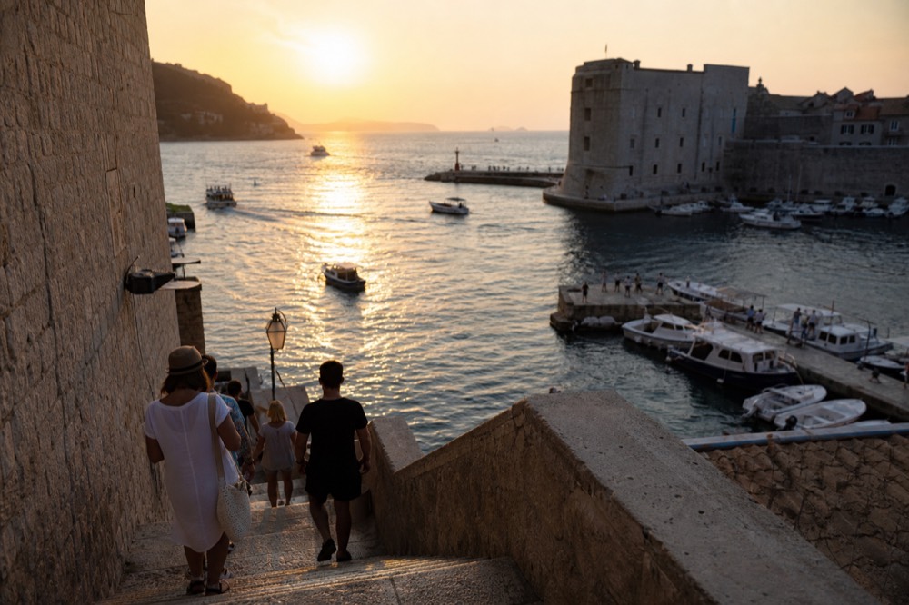 A harbour at dusk with a stone city wall and moored boats