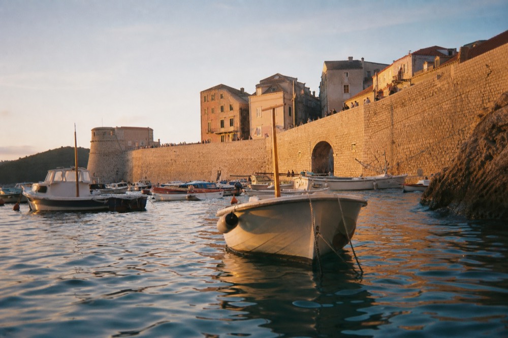 A harbour at morning with several boats and a stone wall in the background