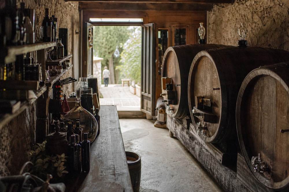 A rustic cellar interior with wooden barrels and bottles on shelves