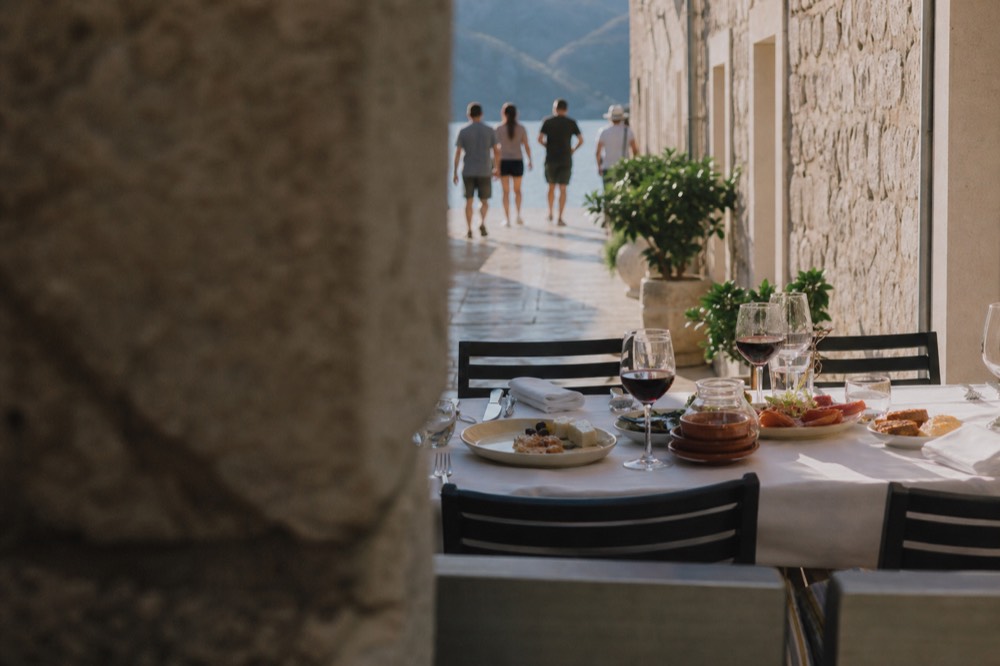 A table set with small plates of food and glasses of red wine in an evening street