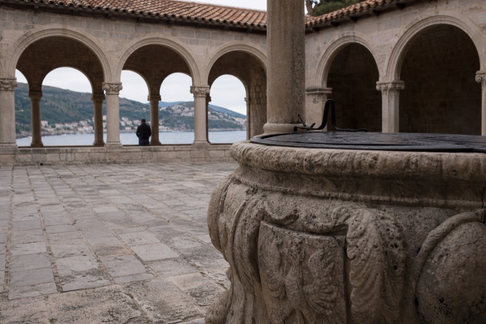 Stone well and arcade in a Dubrovnik monastery courtyard