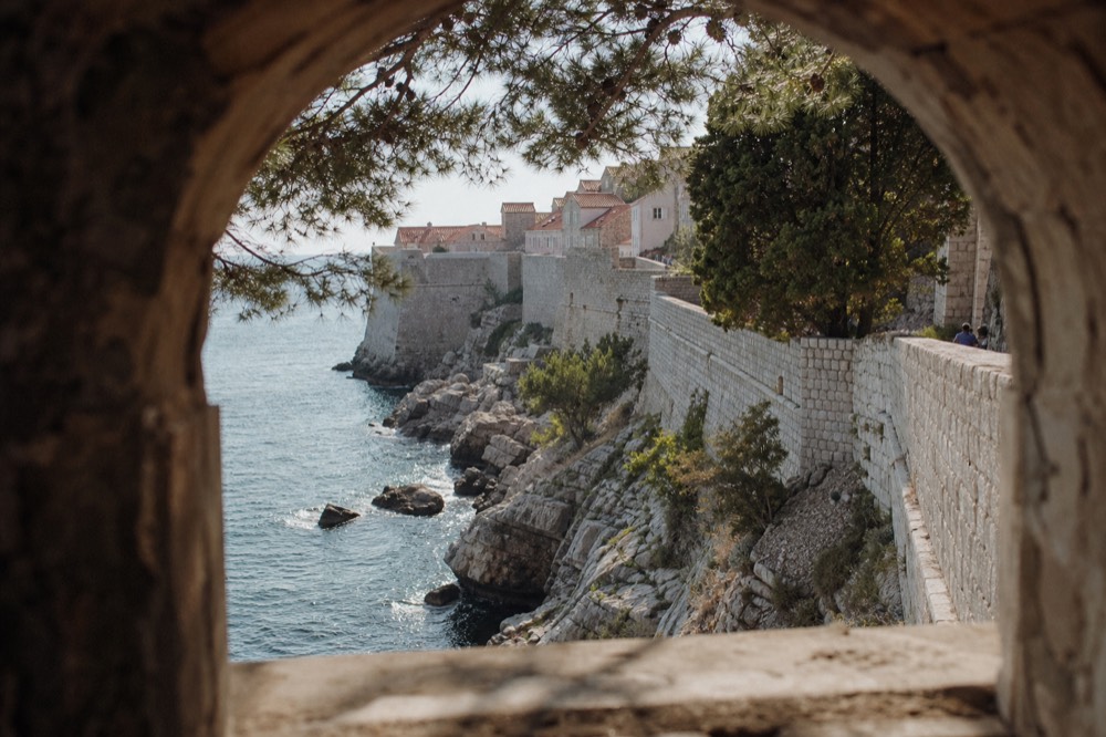 Rocky shoreline with clear blue water below Dubrovnik walls