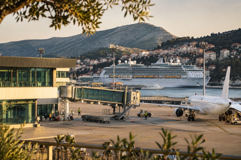 A large cruise ship docked at a port with a historic city rising behind it