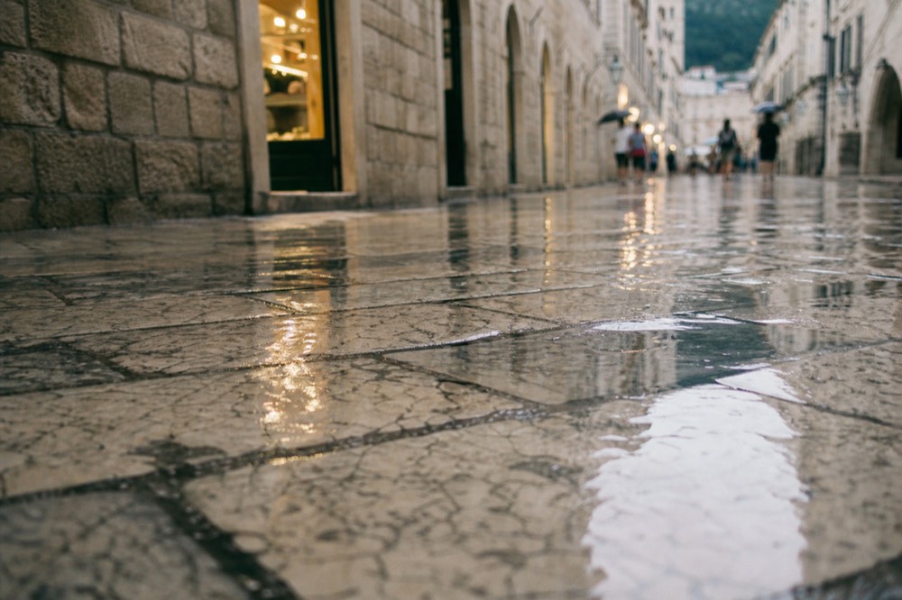 Wet limestone street in Dubrovnik Old Town reflecting shop lights after rain