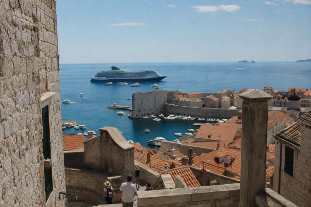 Cruise ship anchored outside Dubrovnik's walled old harbour with tender boats at the quay