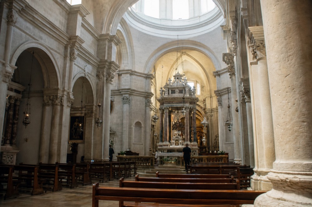 Interior of Dubrovnik Cathedral with stone columns, side altars and light from the dome