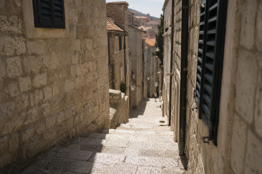 A narrow stone lane in Dubrovnik Old Town with worn steps and shuttered windows