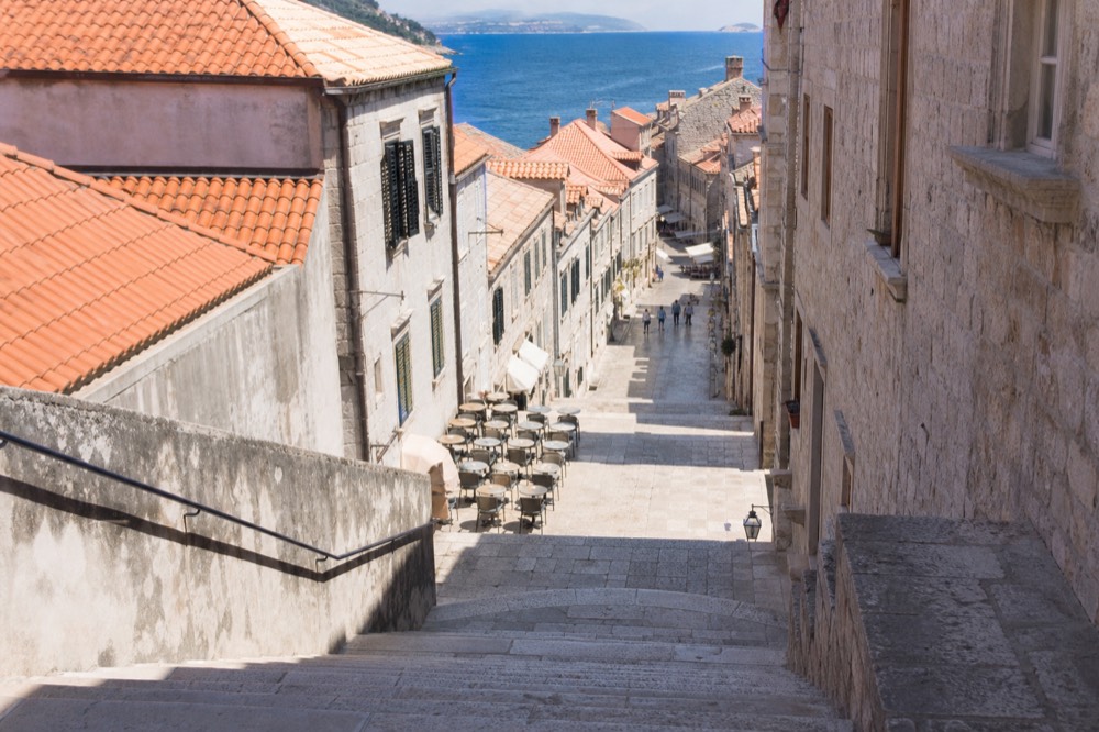 Empty stone steps of the Stradun in soft morning light with café tables set out