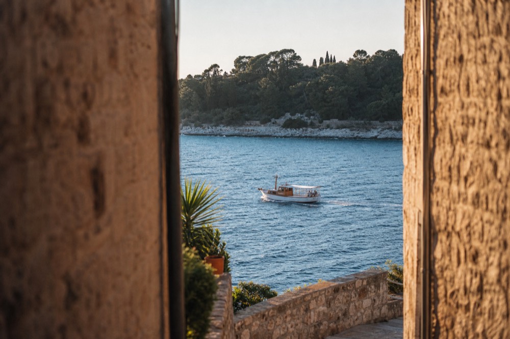 A small boat cruising past wooded Elaphiti island coastline in spring light