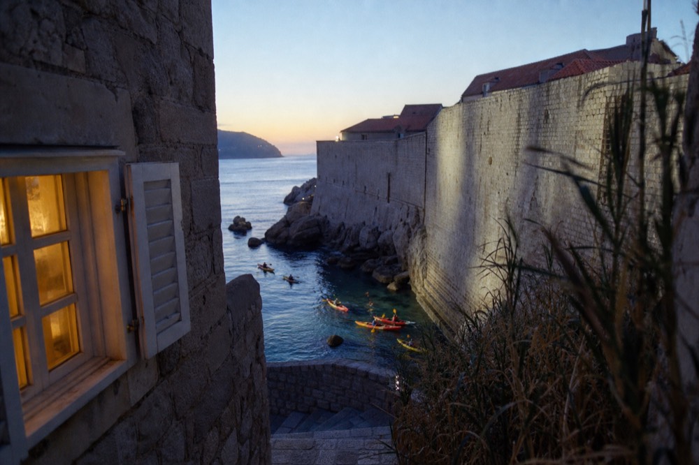 Sea kayakers paddling along the outer city walls of Dubrovnik above clear water