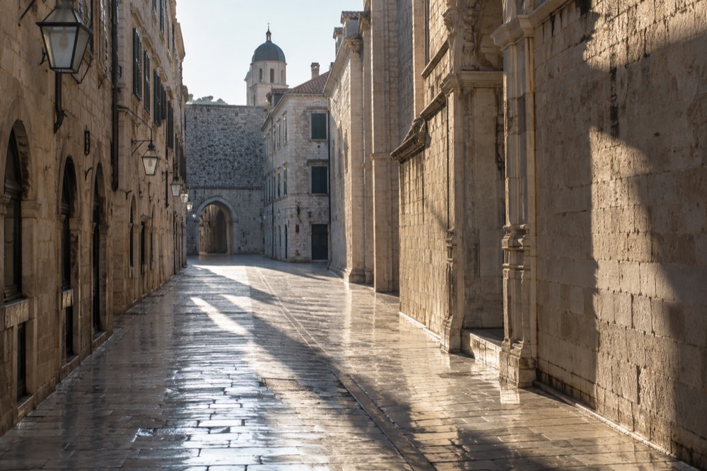Empty morning street inside Dubrovnik Old Town with long shadows on polished stone