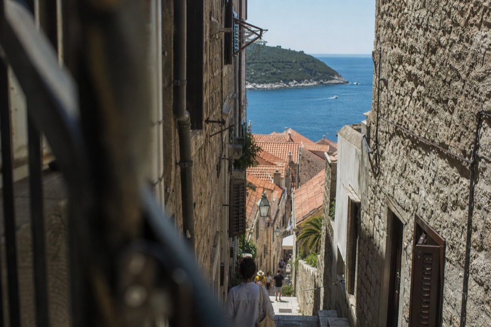 Narrow stone staircase between tall buildings in Dubrovnik Old Town in shade